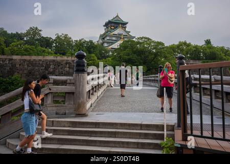 Osaka, Japan, 23. Juni 2024: Touristen überqueren eine Brücke über den inneren Graben, um an einem regnerischen Tag das Schloss Osaka zu betreten. Die Burg ist eine der berühmtesten japanischen Burgen Stockfoto