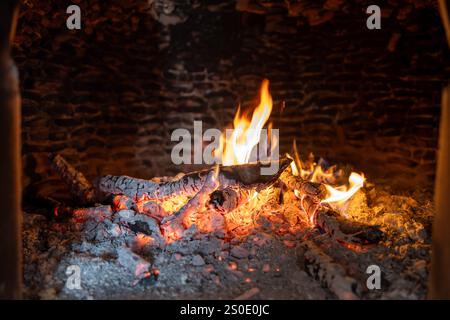 Nahaufnahme von Flammen und glühender Glut in einem rustikalen Holzofen Stockfoto