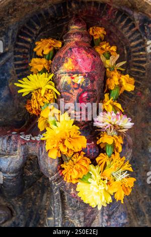 Hübsche Hindufigur oder Statue mit orangefarbenen tagetes Blumen, Panauti, Nepal, Asien Stockfoto