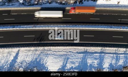 Blick von oben auf Lkw und Auto auf dem verschneiten Winter Highway Stockfoto