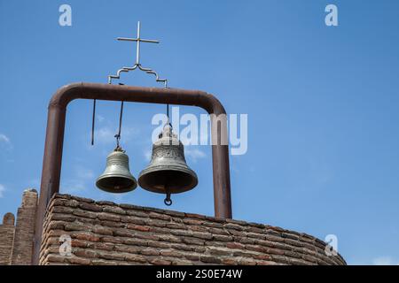 An einem sonnigen Tag in Tiflis, Georgien, hängen alte Glocken unter blauem Himmel Stockfoto