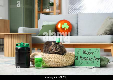 Niedliche Katze im Kobold Hut mit einem Becher grünes Bier und festlicher Postkarte für die Feier zum St. Patrick's Day zu Hause Stockfoto