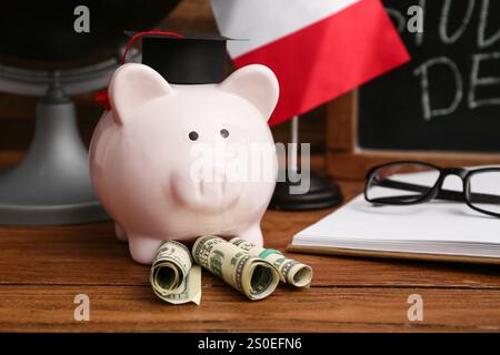 Schweinebank mit Geld auf Holztisch, Nahaufnahme. Studienschuldenkonzept Stockfoto