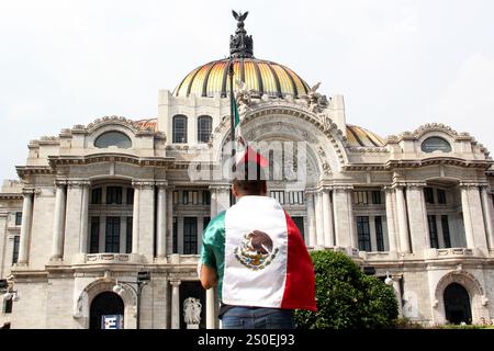 Mexiko-Stadt, Mexiko - 6. September 2023: Der Mann hält die mexikanische Flagge vor dem Palacio de Bellas Artes, um die Nationalfeiertage zu feiern Stockfoto