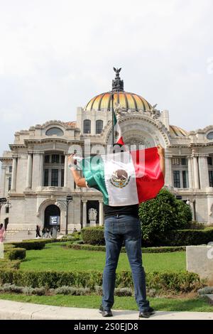 Mexiko-Stadt, Mexiko - 6. September 2023: Der Mann hält die mexikanische Flagge vor dem Palacio de Bellas Artes, um die Nationalfeiertage zu feiern Stockfoto