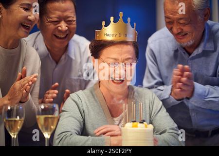 Glückliche ältere asiatische alte Frau, die nachts mit älteren Freunden Geburtstag feiert Stockfoto