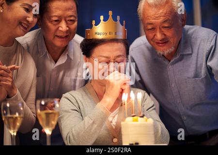 Glückliche ältere asiatische Frau, die mit einer Gruppe alter Freunde Geburtstag feiert Stockfoto