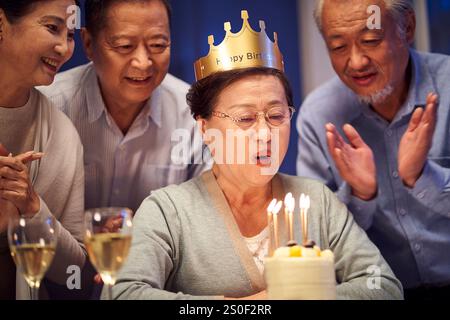 Glückliche ältere asiatische alte Frau, die nachts mit älteren Freunden Geburtstag feiert Stockfoto