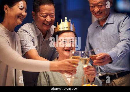 Glückliche ältere asiatische Frau, die mit einer Gruppe alter Freunde Geburtstag feiert Stockfoto