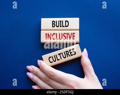 Symbol „integrative Kulturen erstellen“. Holzblöcke mit Wörtern bilden inklusiv-Kulturen. Wunderschöner tiefblauer Hintergrund. Geschäftsmann Hand. Business und Bui Stockfoto