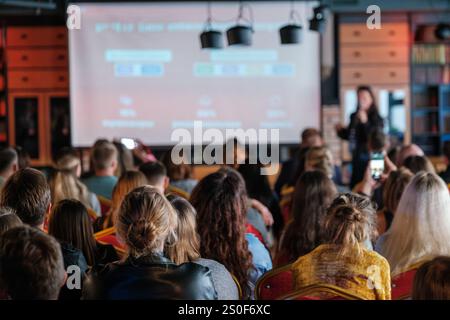 Eine große Menge von Gästen, die eine Vortragspräsentation in einem Konferenzraum mit Projektorleinwand besucht haben Stockfoto