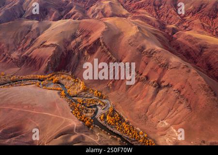 Blick aus der Vogelperspektive auf farbenfrohe rote Berge mit lebhaften Farbtönen, gewundenen Fluss und Herbstlaub. Malerisches und majestätisches Wildnisgebiet, das eine beeindruckende natürliche Komposition schafft, die an marsartige surreale Anregungen erinnert. Stockfoto