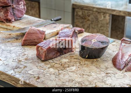 Rohe Thunfischsteaks auf einer Marmorplatte auf einem Fischmarkt, die ihre Textur und Frische zeigen. Dieses Lebensmittelbild hebt hochwertige Zutaten hervor Stockfoto