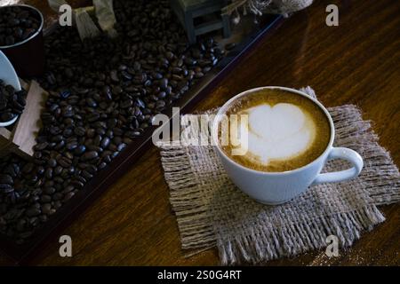 Eine Tasse Latte Art auf Servieren mit Kaffeebenen auf dem Tisch sorgen für eine aromatische Füllung und erwachen einen Tag lang Stockfoto