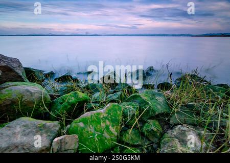 Der Sonnenuntergang am Reservoir ließ die Farben des Abendlichts mit langsamer Verschlusszeit aufnehmen, um alle Wellen sanft zu machen Stockfoto