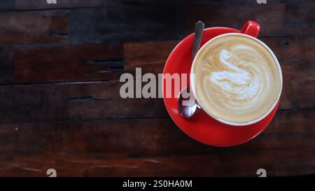 Rote Tasse mit Kaffee auf Holztischhintergrund. Kaffee Glück Stockfoto