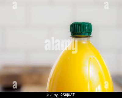 Nahaufnahme einer Plastikflasche Orangensaftgetränk mit grünem Verschluss vor verschwommenem Hintergrund. Stockfoto