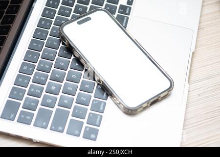 Smartphone mit White Screen Mockup neben Laptop Stockfoto
