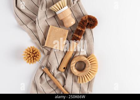 Verschiedene natürliche Reinigungswerkzeuge werden auf einem gestreiften Tuch angezeigt. Die Anordnung umfasst Bürsten, einen Seifenbügel und ein Scheuerpad, das ECO-f hervorhebt Stockfoto