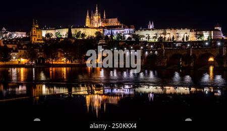 Ein atemberaubender nächtlicher Blick auf die Prager Burg, beleuchtet gegen den Nachthimmel, reflektiert in der Moldau. Die berühmte Karlsbrücke ist im zu sehen Stockfoto