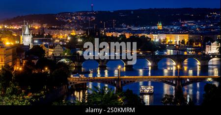 Ein atemberaubender nächtlicher Blick auf Prag mit beleuchteten Brücken über die Moldau, historischen Gebäuden und einer lebhaften Skyline. Stockfoto