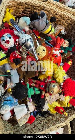 Ein Korb aus Korb mit einer vielfältigen Kollektion kleiner, handgefertigter Textilspielzeuge. Die Spielzeuge sind überwiegend rot, gelb und blau, mit verschiedenen Farben Stockfoto