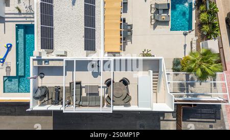 Blick aus der Vogelperspektive auf eine stilvolle Villa mit Solarpaneelen, Dachterrasse, privatem Pool, Sitzgelegenheiten im Freien und üppiger Landschaftsgestaltung in Torrevieja. Stockfoto