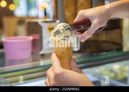 Vanilleeis mit Schokoladenstückchen wird in eine Waffel mit einem Eislöffel gefüllt, Herbstkreationen im Cafe Kuh, Deckenpfronn, Deutschland, Europa Stockfoto