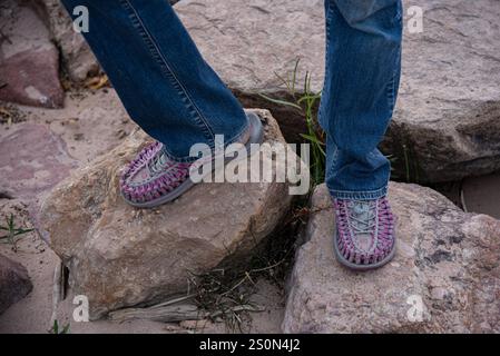 Schuss von Beinen aus den Knien in blauer Jeans und Füße in pinken Uneek Sneakers, die draußen auf Felsen stehen, USA. Stockfoto