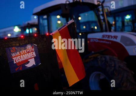 Augsburg, Deutschland. Dezember 2024. Die Teilnehmer einer Demonstration nehmen an einem marsch mit einem Traktor mit der Aufschrift „Wir stehen zusammen“ Teil. Die Kundgebung wurde vom Bürgerforum Schwaben initiiert. Laut der Ankündigung beschäftigen sich die Teilnehmer unter anderem mit sozialen Problemen, Frieden und "Deutschland zuerst". Kredit: ---/dpa/Alamy Live News Stockfoto