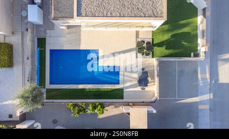 Blick von oben auf eine stilvolle Vistabella Villa mit geometrischem privatem Pool, Terrasse, Garten und Sitzgelegenheiten im Freien. Stockfoto