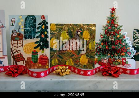 Weihnachtskarten auf grauem Marmorkamin mit rotem Band und recycelten Schleifen. Stockfoto