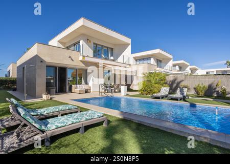 Elegante zweistöckige Villa in Vistabella in der Nähe von Torrevieja, Spanien, mit privatem Pool, Liegestühlen, Landschaftsgarten und modernem Design. Stockfoto