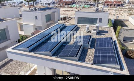 Energieeffizientes Dach mit mehreren Solarpaneelen in einem modernen Haus, das Lösungen für erneuerbare Energien in einem urbanen Umfeld präsentiert. Stockfoto