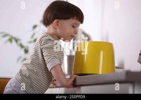 Kleiner Junge, der mit Toaster in der Küche spielt. Gefährliche Situation Stockfoto