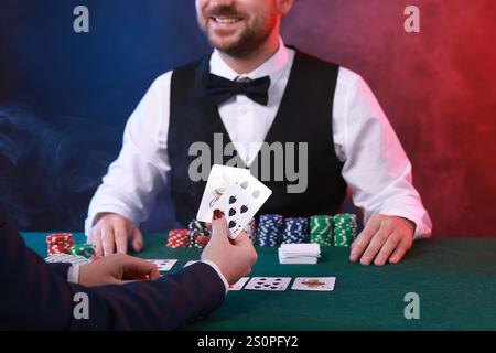 Professioneller Croupier und Spieler am Tisch mit Spielkarten und Casino-Chips, Nahaufnahme Stockfoto