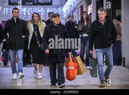 Cambridge, Großbritannien. Dezember 2024. Shopper mit Taschen laufen durch das Einkaufszentrum Lion's Yard. Trotz der schlechten Wirtschaftsleistung in den letzten Monaten des Jahres 2024 und der drohenden Rezession gehen Käufer auf die Straße, um die Vorteile der Weihnachtsverkäufe im Stadtzentrum von Cambridge zu nutzen. Quelle: SOPA Images Limited/Alamy Live News Stockfoto