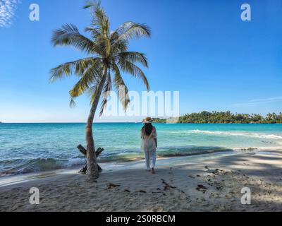 Ein ruhiger Spaziergang führt entlang der atemberaubenden Küste von Koh Kood, Thailand, wo sanfte Wellen die Sandküste küssen und ein Alleinreisender die Sonne genießt Stockfoto