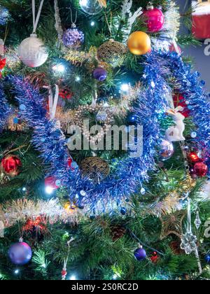 Farbenfroher Weihnachtsbaum mit festlichen glitzernden Dekorationen, Lametta, Kugeln, Lichtern und Ornamenten Stockfoto