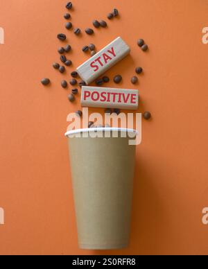 Symbol „positiv bleiben“. Konzeptwort bleibt positiv auf Holzblöcken. Schöner oranger Hintergrund mit Kaffeetasse. Business und bleiben positiv. Co Stockfoto