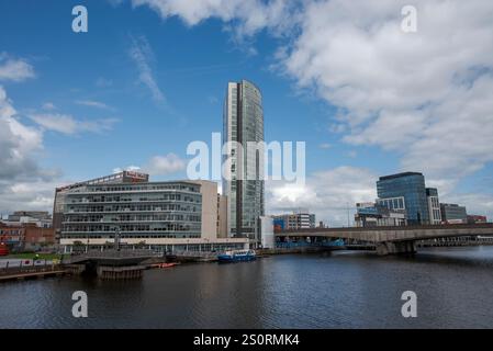 BELFAST, NORDIRLAND – 4. AUGUST 2023: Brücke über den Fluss Lagan in Belfast mit modernen Gebäuden unter bewölktem Himmel Stockfoto