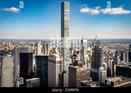 Blick aus der Luft auf eine moderne Skyline der Stadt mit einem hohen Wolkenkratzer inmitten anderer Gebäude, mit einem klaren blauen Himmel und verstreuten Wolken im Hintergrund. Stockfoto
