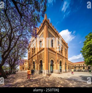 Historisches Wahrzeichen im Neo-Mudéjar-Stil mit kunstvoller Architektur und blühenden Jacaranda-Bäumen in Sevilla. Stockfoto