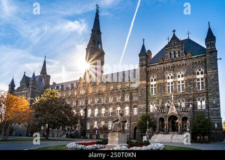 Ein historisches Universitätsgebäude mit einem Uhrenturm, mit komplizierter Steinarchitektur. Die Sonne untergeht hinter dem Turm und schafft einen Sternensprung Stockfoto