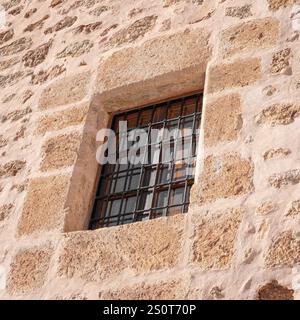 Alte spanische Steinmauer mit einem Metallgitter als Gefängnis in Spanien, um zu entkommen. Rosa- und Orangetöne. Der Begriff Freiheit und Freiheit Stockfoto
