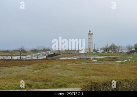 Leuchtturm hoch am Ufer an einem bewölkten Tag mit einem Holzpier im Vordergrund Stockfoto