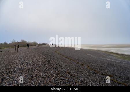 Spaziergang am Kiesstrand unter bewölktem Himmel bei Ebbe in der Nähe eines Küstengebiets Stockfoto