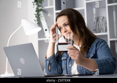 Eine gestresste Frau, die sich mit Online-Shopping beschäftigt und mehrere Optionen sorgfältig auf ihrem Laptop vergleicht, während sie Momente der Besinnung und des Nachdenkens durchlebt Stockfoto