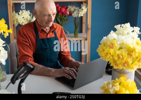 Porträt eines Unternehmermannes, der im eigenen Blumenladen sitzt und an einem Laptop arbeitet. Kopierbereich Stockfoto