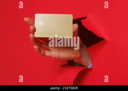 Zugeschnittene Ansicht der Frau Hand, die durch Papier reißt und Kreditkarte hält, die Bankkredite zum Kauf bekommt, isoliert auf rotem Hintergrund. Stockfoto